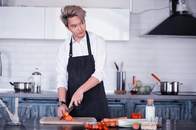 A young Asian cook in the kitchen prepares food in a cook suit