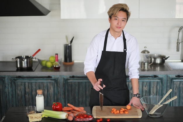 A young Asian cook in the kitchen prepares food in a cook suit