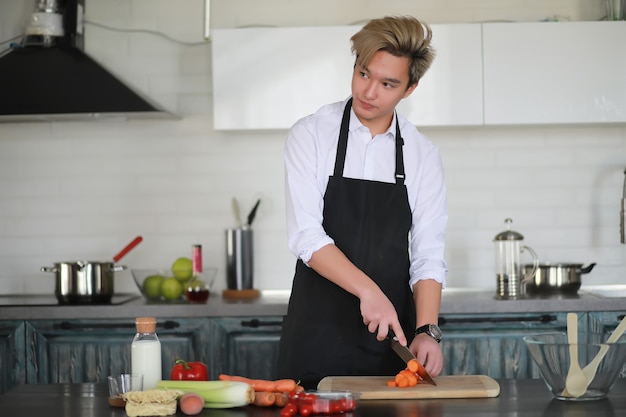 A young Asian cook in the kitchen prepares food in a cook suit