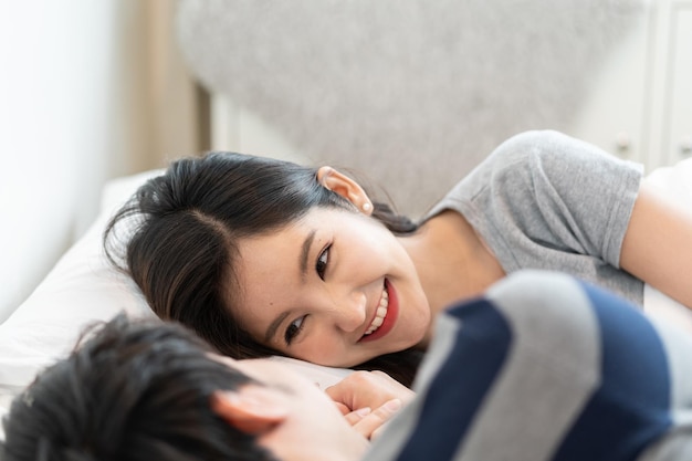 Young asian couple on bed in bedroom hug and enjoy life together and smiling in the morning with happiness