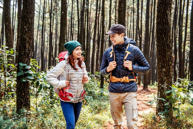 Young asian couple hikers with backpack walking