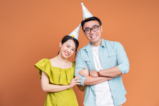 Young Asian couple holding birthday cake on background