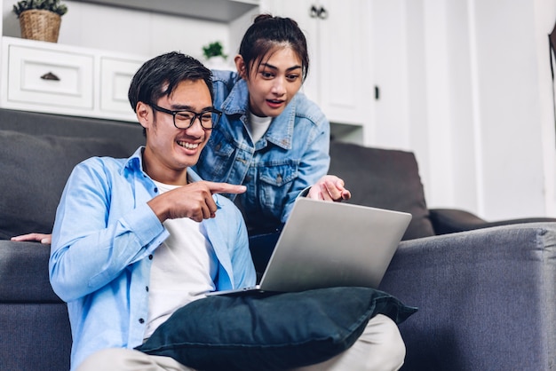 Young asian couple relaxing using laptop computer working and video conference meeting online chat.