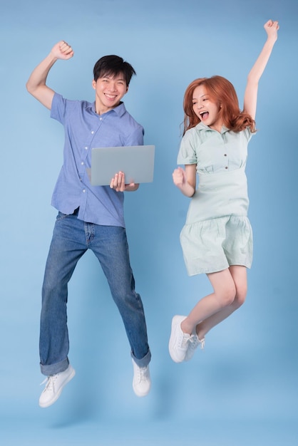 Young Asian couple using laptop on blue background