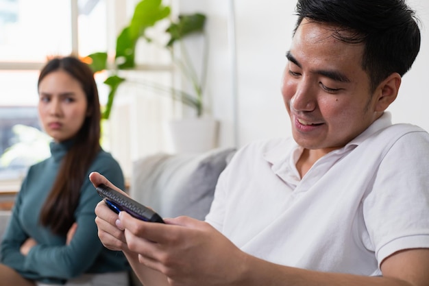 Young Asian couple in which the man plays the game and ignores his wife