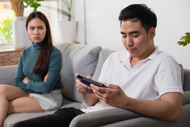 Young Asian couple in which the man plays the game and ignores his wife