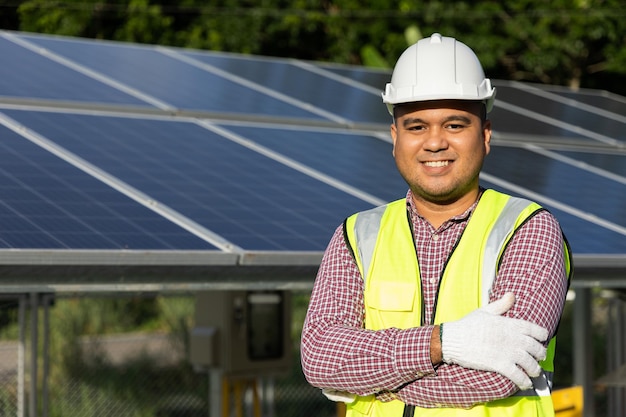 Young asian electrical engineer standing in front of Solar cell panels farm. He checking and installing. Solar generator power concept.