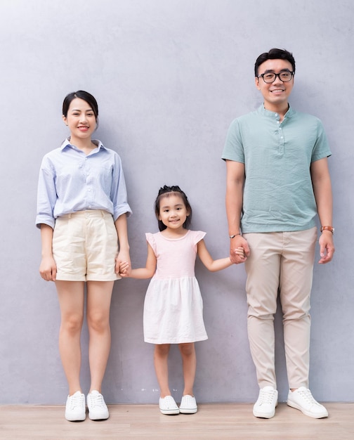 Young Asian family standing on background