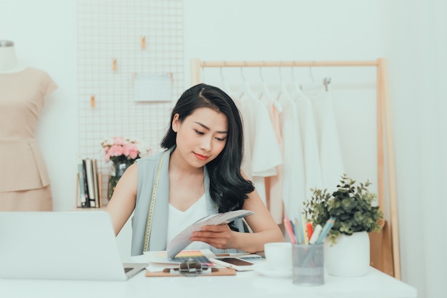 Young Asian fashion designer choosing color for her new collection