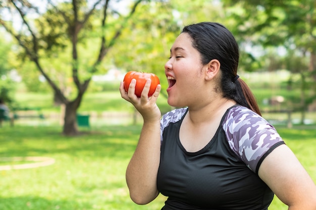 young Asian Fat woman holding red tomato on nature park