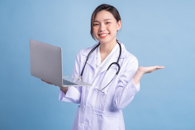 Young Asian female doctor standing on blue background