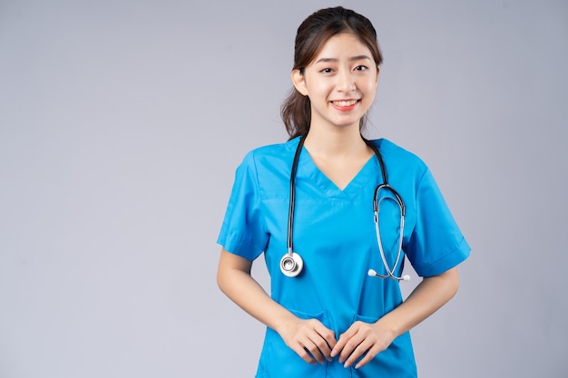 young Asian female doctor wearing blue uniform on grey