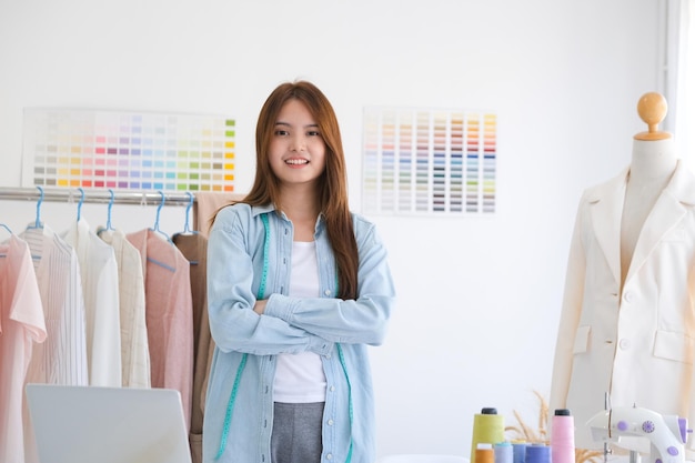 A young asian female fashion designer is standing with arms folded confident and looking at camera.