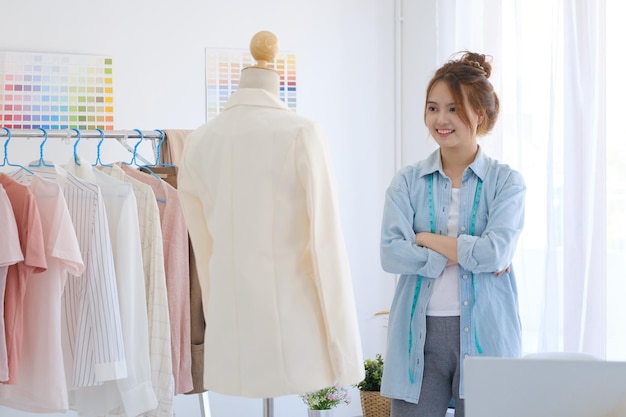 A young asian female fashion designer is standing with arms folded confident and looking at camera.