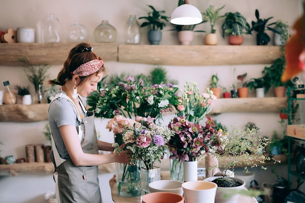 Young Asian female florist owner of small business flower shop making beautiful floral arrangements over the counter in workplace Enjoying her job to be with the flowers Small business concept