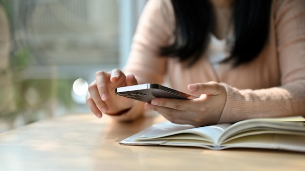 Young Asian female using his phone while relaxing in the library or coffee shop cropped image