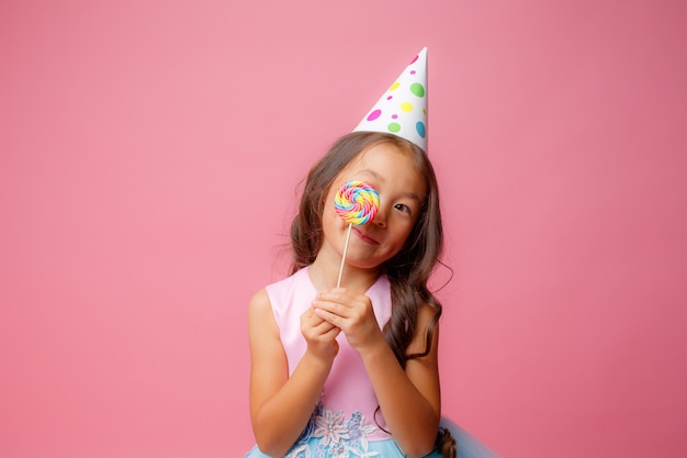 Young Asian girl at a birthday party with a Lollipop on a pink 