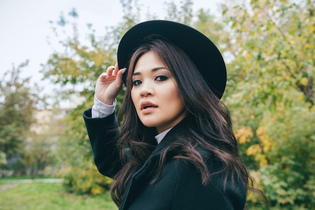 Young asian girl in dark coat and hat