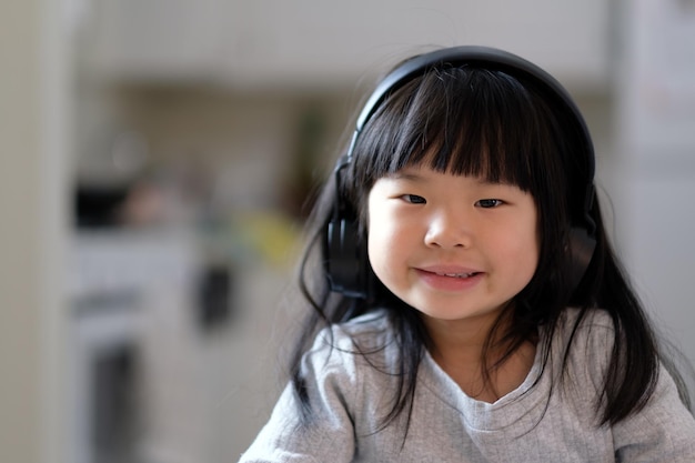 A young asian girl enjoying listening to music on her headphone