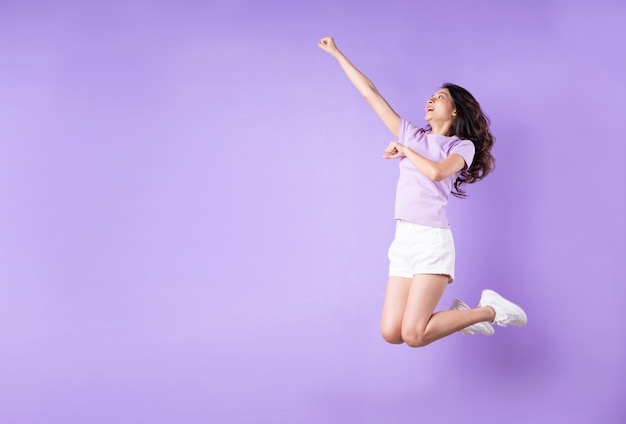 Young asian girl jumping up on purple background