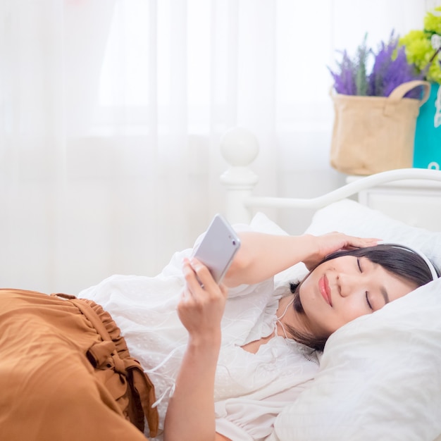 Young asian girl listening to the music in bed