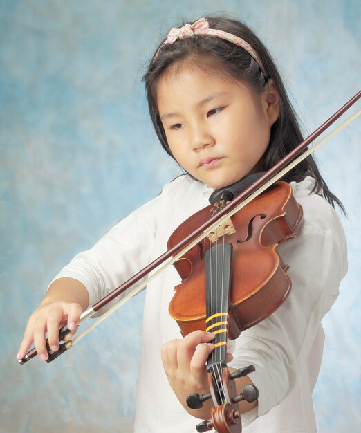 Young asian girl long hair played violin against sky blue background