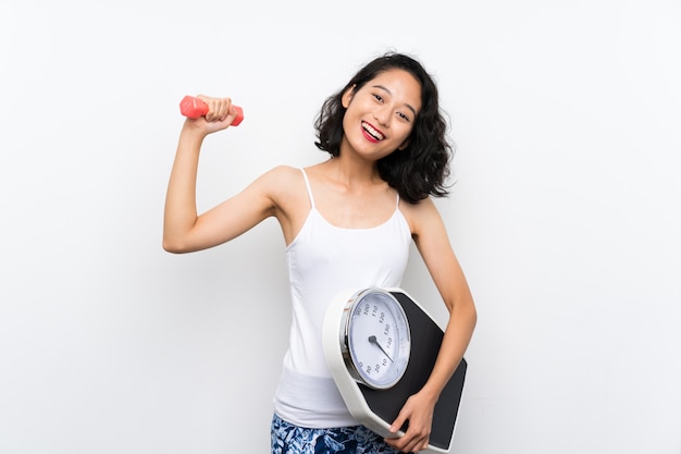 Young Asian girl making weightlifting and with weighing machine