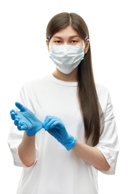 Young asian girl in medical mask wearing blue gloves on white background isolated