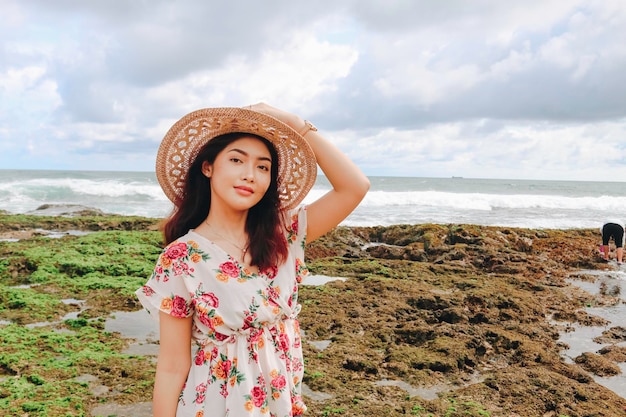 A young Asian girl wearing beach hat is relaxing on the blue sky beach at Gunungkidul Indonesia