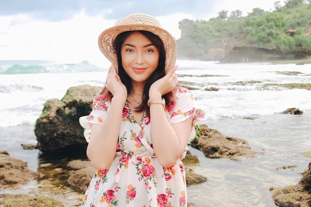 A young Asian girl wearing beach hat is relaxing on the blue sky beach at Gunungkidul Indonesia