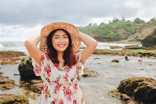 A young Asian girl wearing beach hat is relaxing on the blue sky beach at Gunungkidul Indonesia