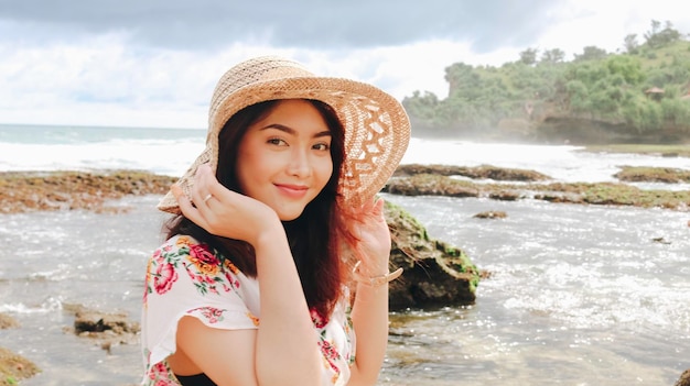 A young Asian girl wearing beach hat is relaxing on the blue sky beach at Gunungkidul Indonesia