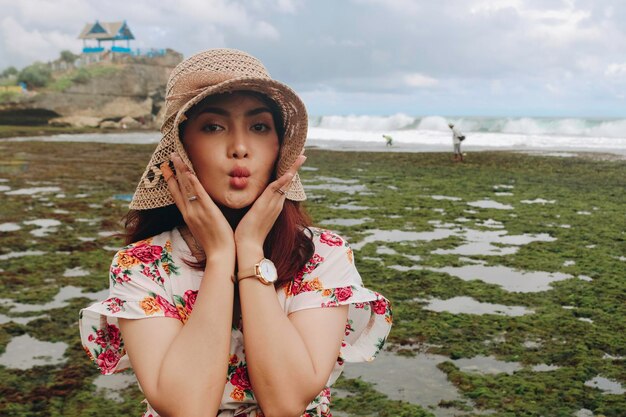 A young Asian girl wearing a beach hat is relaxing on the blue sky beach at Gunungkidul Indonesia