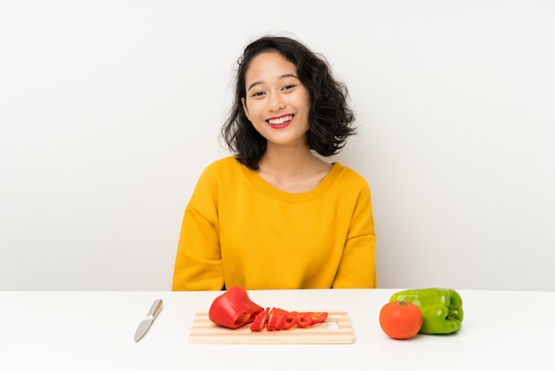 Young asian girl with vegetables in a table with surprise facial expression