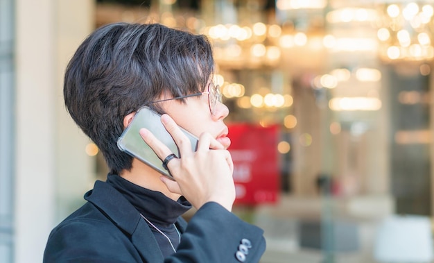 Young Asian guy using cellphone Asian man talking on smartphone outdoor