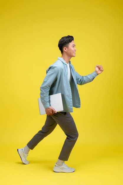 A young Asian handsome male student with a laptop in hand smart casual outfit