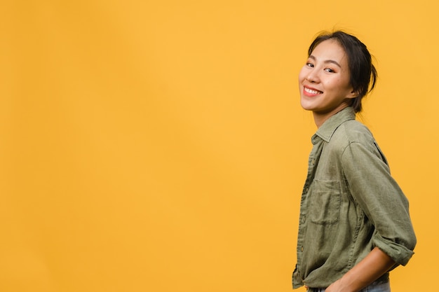 Young Asian lady with positive expression, smile broadly, dressed in casual clothing  over yellow wall. Happy adorable glad woman rejoices success. Facial expression concept.