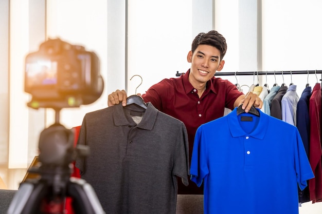 Young Asian male online merchant blogger using camera to live video to review and sell product Social media Influencer and online shopping concept