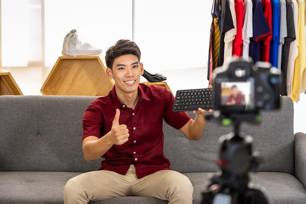 Young Asian male online merchant blogger using camera to live video to review and sell product with thumb up Social media Influencer and online shopping concept