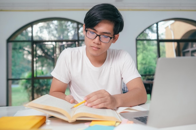 Young Asian male student is preparing to reading a books for exams at university