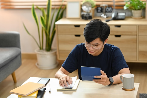 Young asian male using calculator for calculating money bank loan rent payments managing expenses finances