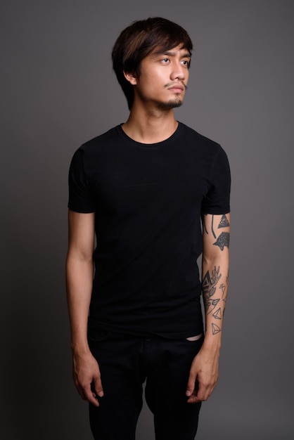 Young Asian man against gray wall