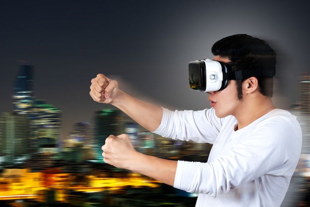 Young asian man in casual white outfit holding or wearing VR glasses goggles 