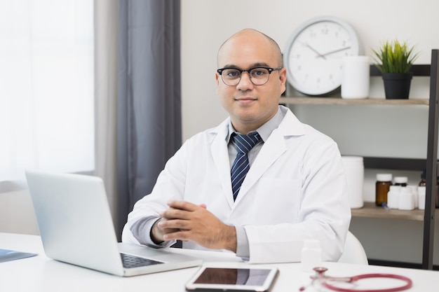 Young asian man doctor works from home working online looking and camera talking with patient Explain about taking medications to treat illnesses