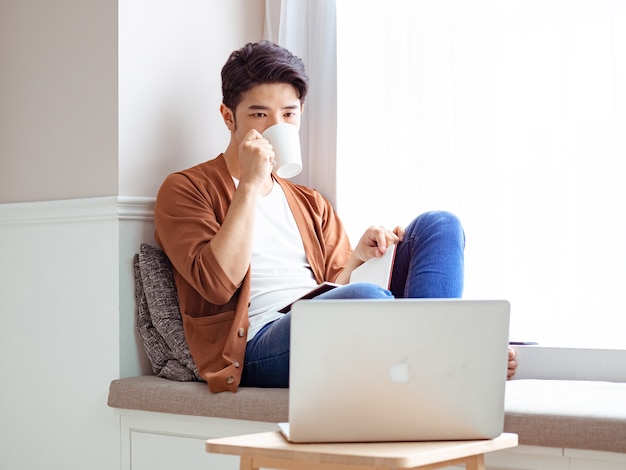 Young asian man drinking while relaxing at home