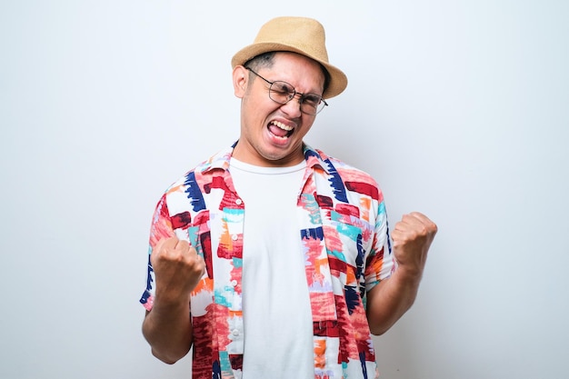 Young asian man happy and excited doing winner gesture with arms raised smiling and screaming