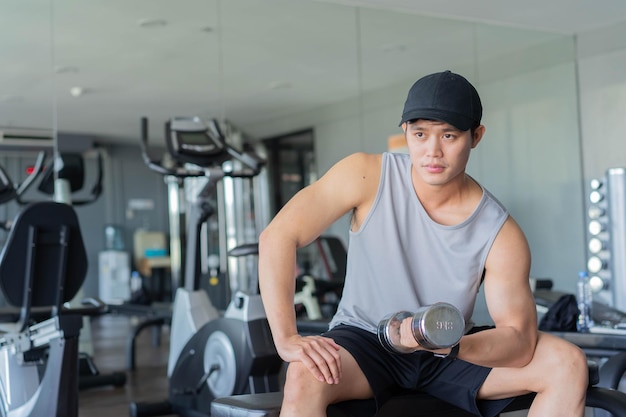 young asian man hold dumbbell for gaining bicep muscle