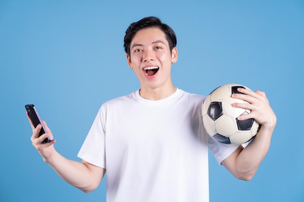 Young Asian man holding ball on background