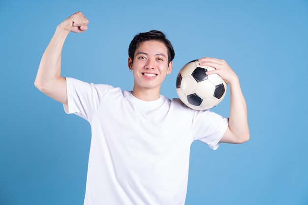 Young Asian man holding ball on background