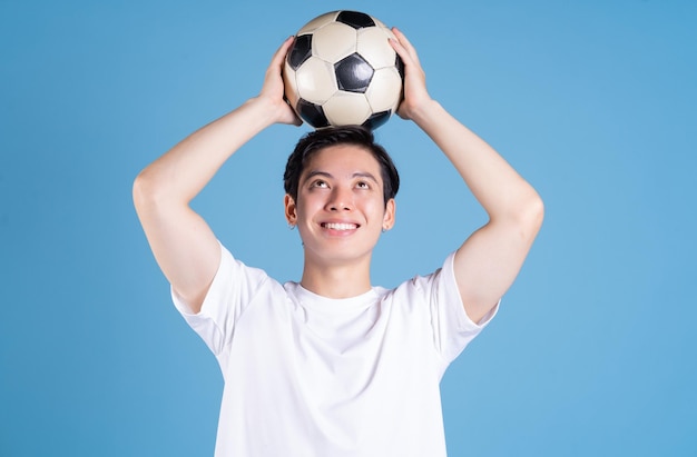 Young Asian man holding ball on background